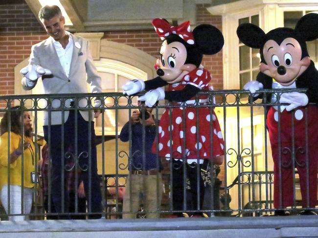 With Minnie and Mickey Mouse, Walt Disney World President Josh D'Amaro waves to guests gathered on Main Street USA, in the Magic Kingdom in the final minutes before the park closed, Sunday night, March 15, 2020, in Lake Buena Vista, Fla. Walt Disney World announced that all their park will be closed for the rest of March as a result of the coronavirus pandemic. (Joe Burbank/Orlando Sentinel)/Orlando Sentinel via AP)