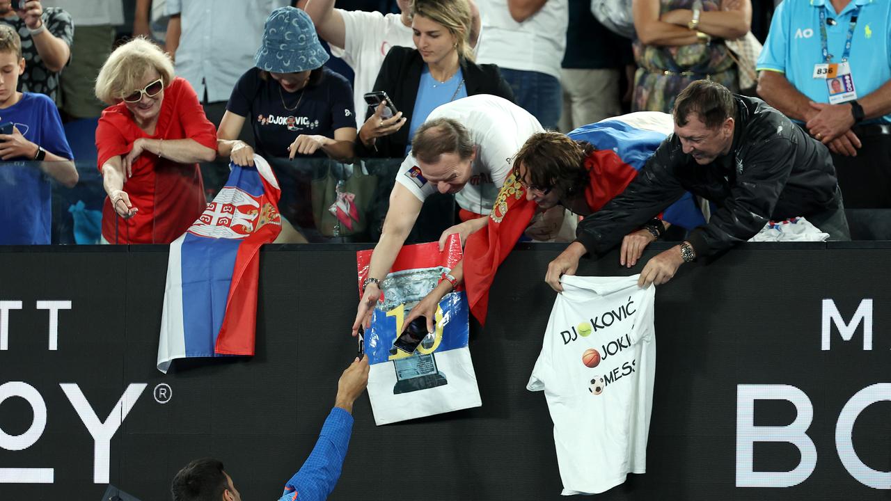 Novak Djokovic dari Serbia menandatangani merchandise untuk penonton. Pria di sebelah kanan menutupi baju 'Z' setelah diminta oleh ofisial (kanan belakang).  Foto oleh Cameron Spencer/Getty Images
