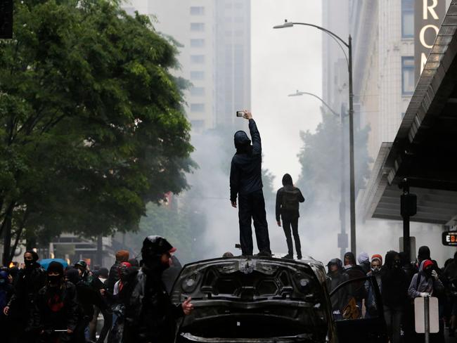 People stand on burned vehicles following demonstrations. Picture: Jason Redmond