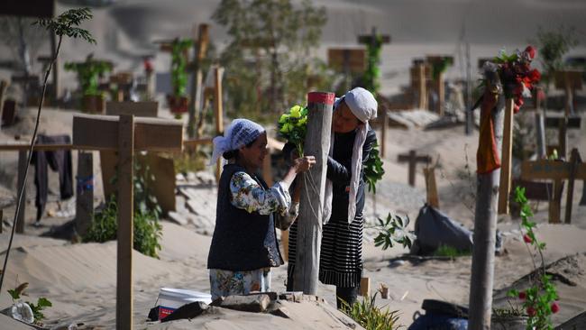 Women decorate a Uighur grave on the outskirts of Hotan in Xinjiang. Picture: AFP