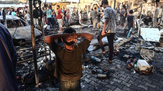 A Palestinian boy gestures as people check the destruction following an Israeli airstrike on a camp for displaced people inside the walls of Al-Aqsa Martyrs Hospital in central Gaza.