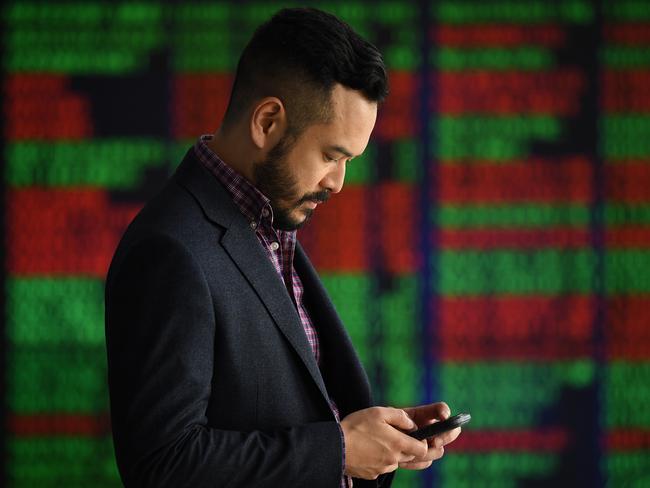 A man checks his phone in front of digital market boards at the Australian Stock Exchange (ASX) in Sydney, Monday, March 2, 2020. The Australian share market spiralled nearly 2.5 per cent lower as the deadly coronavirus spreads across the planet and stifles trading prospects. (AAP Image/Joel Carrett) NO ARCHIVING