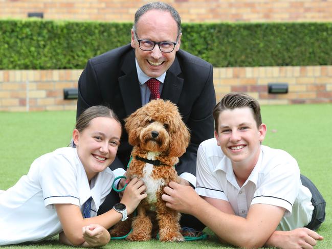 Emmanuel College students Indianna Morris, 13, and James Gilmore, 14, with principal Daniel Brown and wellness dog Mylo. Picture: Glenn Hampson.