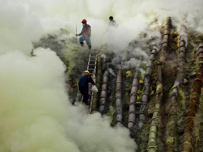 BANYUWANGI, EAST JAVA - DECEMBER 17:  A sulfur miner carries a goats head in a white bag as he climbs to bury the head in the crater as part of an annual offering ceremony on the Ijen volcano on December 17, 2013 in Yogyakarta, Indonesia. The ritual is performed by the sulfur miners of Mount Ijen who slaughter a goat and then bury the head in the crater of mount Ijenn. The sacrifice is performed to ward off potential disasters for the next year. The Ijen crater rises to 2,386m, with a depth of over 175m, making it one of the world's largest craters. Sulphur mining is a major industry in the region, made possible by an active vent at the edge of a lake, but the work is not without risks as the acidity of the water in the crater is high enough to dissolve clothing and cause breathing problems. (Photo by Ulet Ifansasti/Getty Images)