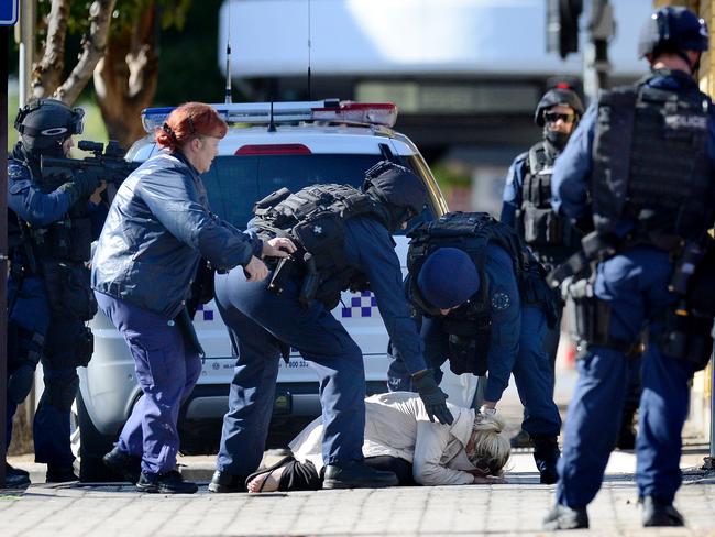 A woman slumps on the ground after leaving Marilyn’s Studio during the city siege involving Rodney Clavell. Picture: Tom Huntley