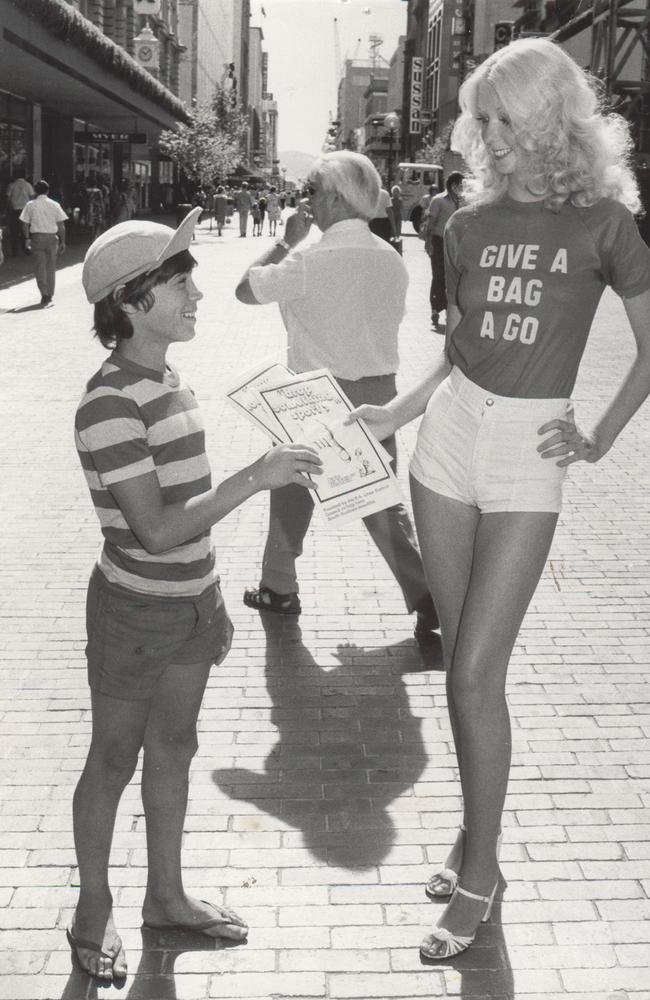 Model Debbie Mead, 16, of Para Hills, in Rundle Mall handing David Buhagiar, 12, of Devon Park, a rubbish bag as part of KESAB’s 1977 ‘Give a Bag a Go’ promotion.