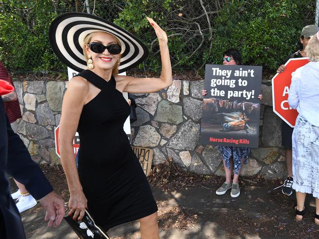 A racegoer walks past animal welfare activists as they protest outside the Eagle Farm racecourse. Picture: AAP/Dan Peled