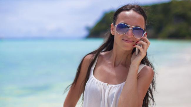 Young beautiful woman at the beach talking on her phone