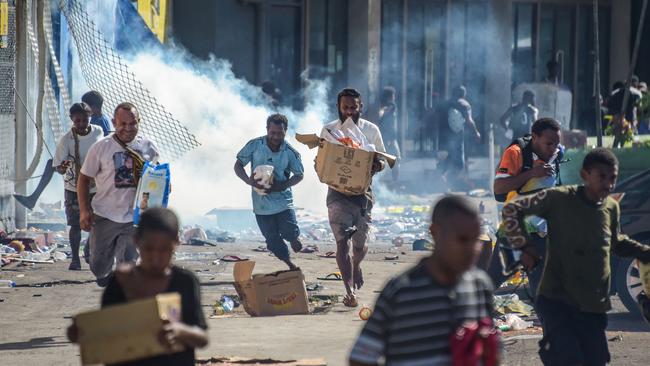 People run with merchandise as crowds leave shops with looted goods amid a state of unrest in Port Moresby on January 10, 2024. Picture: AFP