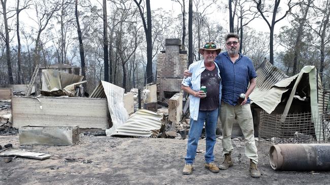 Steve Napier and Tony Foulis share a beer for their friend Michael Clarke in the ruins of his home. Picture: Gaye Gerard