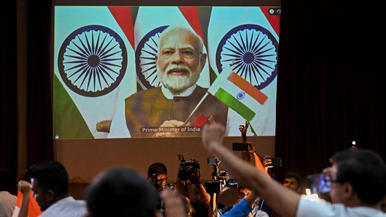 People wave India's national flag as Prime Minister Narendra Modi congratulates the Indian Space Research Organisation (ISRO) for the successful lunar landing of the Chandrayaan-3 spacecraft on the south pole of the moon. Picture: Punit Paranjpe/AFP