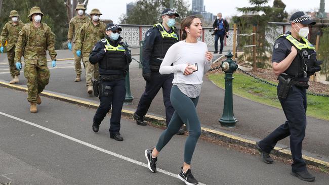 ADF personnel and police on patrol along the Yarra in Melbourne on day one of the city’s mandatory mask-wearing. Those exercising are exempt. Picture: David Crosling