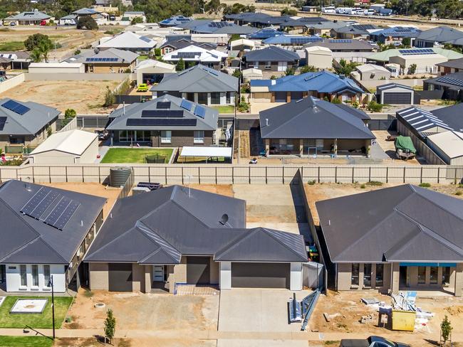 Aerial view, new rural housing development being built on former quality food-producing farmland. Railway line for freight transport and tourist trains can be seen in the background with potential for commuter trains. Close view of houses