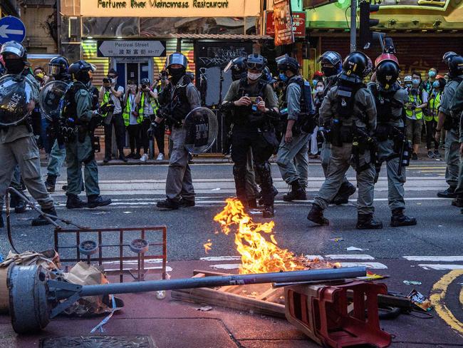 Police walk past a burning barricade set up by protesters. Picture: AFP