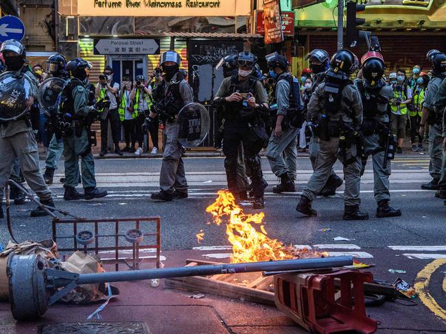 Police walk past a burning barricade set up by protesters. Picture: AFP