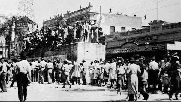 Townsville crowds celebrating Victory in the Pacific on 25 August 1945. Also shown is the concrete air raid shelter in Flinders Street.