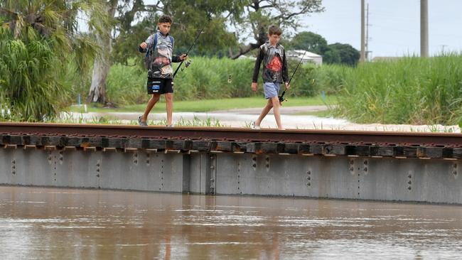 Sunday February 9. Heavy rain causes flooding in North Queensland. Flooding at Plantation Creek in Ayr cuts Bruce Highway to traffic apart from trucks. Boys leave nearby rail bridge for safety. Picture: Evan Morgan