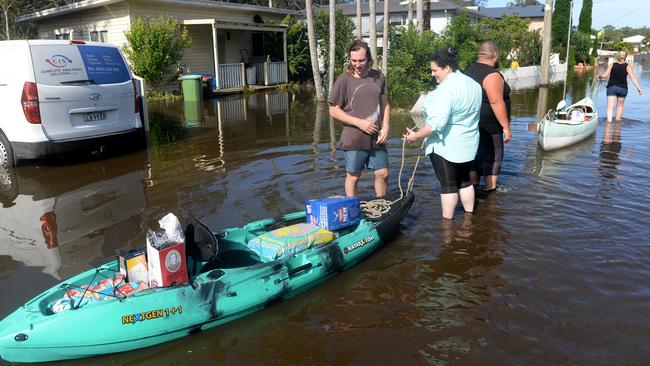 Chittaway residents take to the flooded street in water craft. Picture: Jeremy Piper