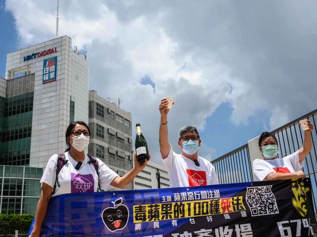 Pro-government activists celebrate with champagne outside the offices of the local Apple Daily newspaper in Hong Kong.