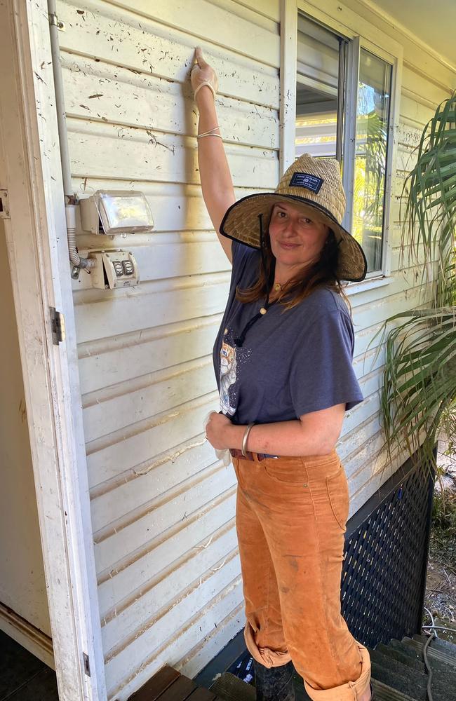 Carlie Daley shows where floodwaters reached at her home.