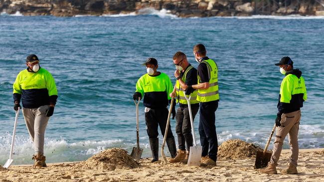 Workers clean up Coogee Beach after it was closed due to some unidentified pollution that has washed up. Picture: Justin Lloyd