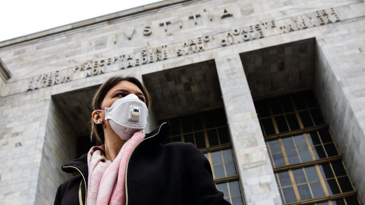 A woman wearing a respiratory mask exits from the Palace of Justice in Milan.