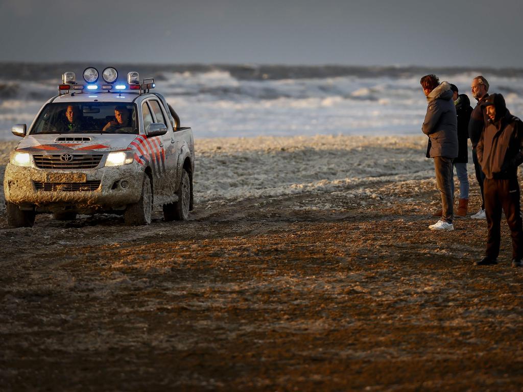 People look at a police car on a beach after a group of surfers was reported in trouble at the Noordelijk Havenhoofd, near the coastal town of Scheveningen.