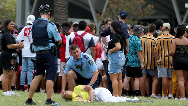 Two police officers helping a girl passed out on the ground. Picture: Damian Shaw