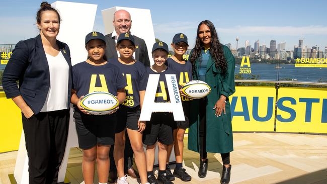 Shannon Parry (l) of the Wallaroos, Wallaroos head coach Jay Tregonning (c) and Mahalia Murphy (r) of the Wallaroos pose with junior rugby players during an Australian Rugby World Cup Bid event.