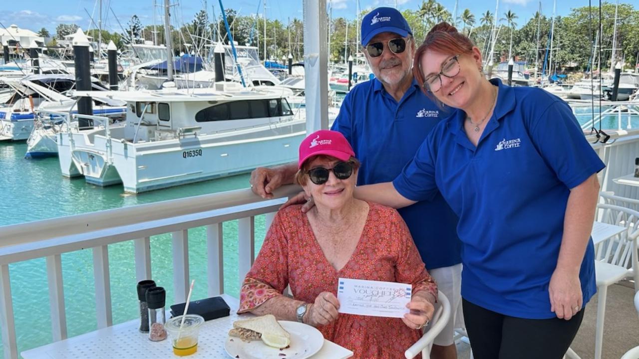 Regular visitor Jossie Populin receives a prize after buying Maina Coffee's 1000th crab sandwich from the business' owner Ron Barker and manager Brydy Stanfield. Picture: Supplied.