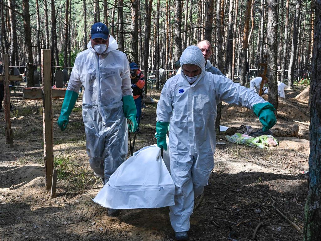 Forensic technicians carry a body bag at the site of a mass grave in a forest on the outskirts of Izyum, eastern Ukraine. Picture: AFP