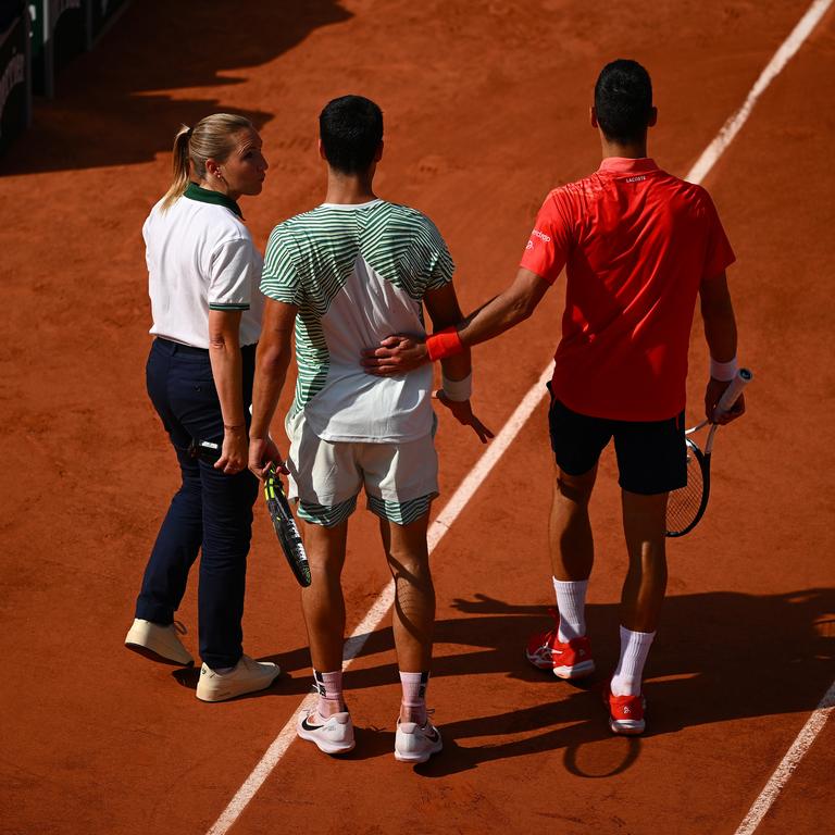 Djokovic places a friendly hand on Alcaraz’s back after his cramping flared early in the third set. (Photo by Clive Mason/Getty Images)