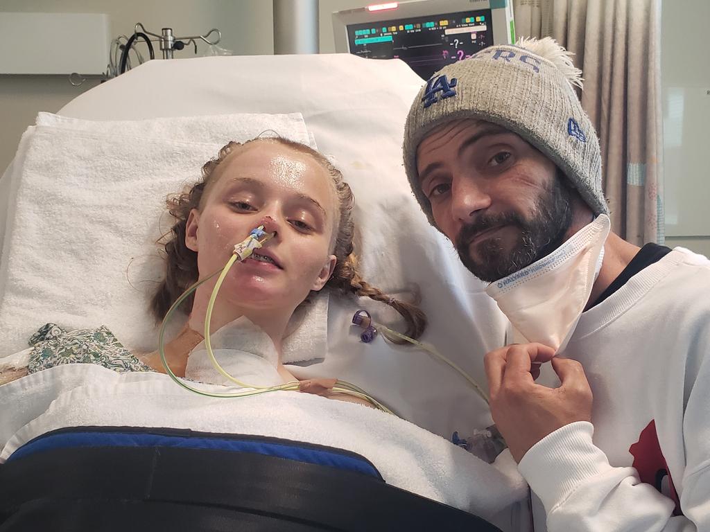 Tyra was recently able to stand upright with assistance from a machine. Her Father Ashley Johnson (right) said the physical and emotional trauma of the ordeal has been difficult. Picture: Supplied