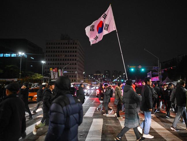 A man holds the South Korea flag outside the National Assembly. (Photo by ANTHONY WALLACE / AFP)