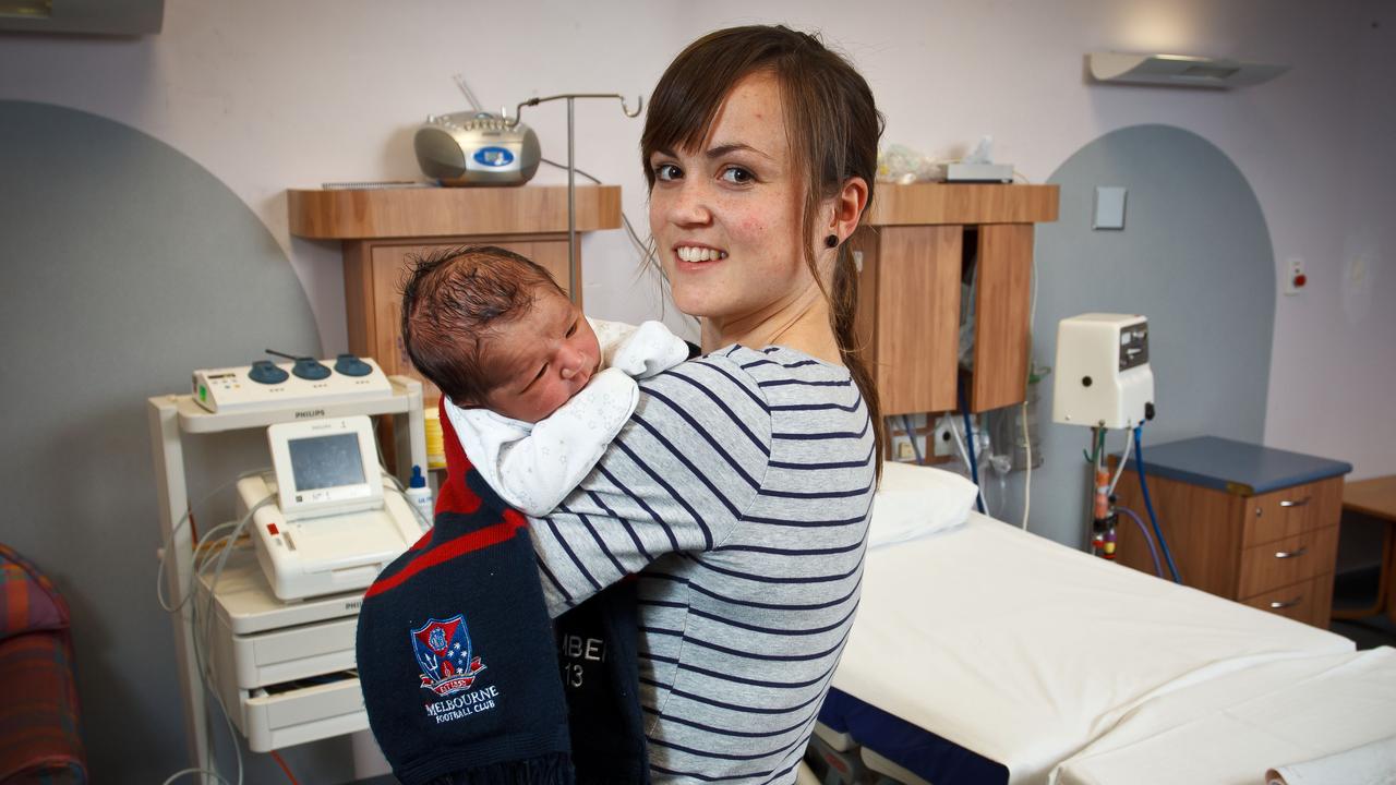 Daisy Pearce the midwife holds a baby after being drafted by Melbourne for an AFLW exhibition match.