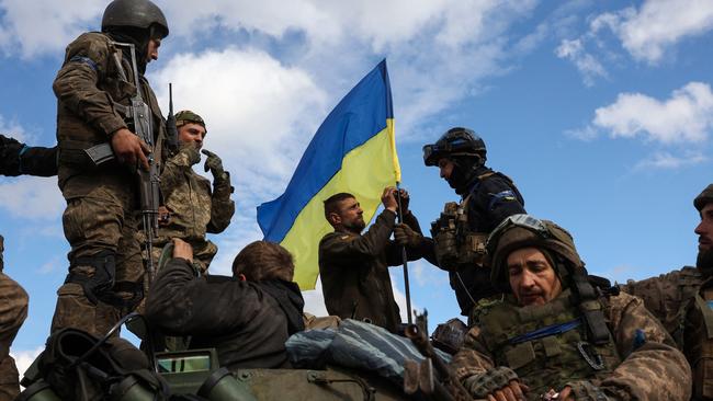 Ukrainian troops adjust their national flag atop an armoured personnel carrier near Lyman in the Donetsk region on Tuesday. Picture: AFP