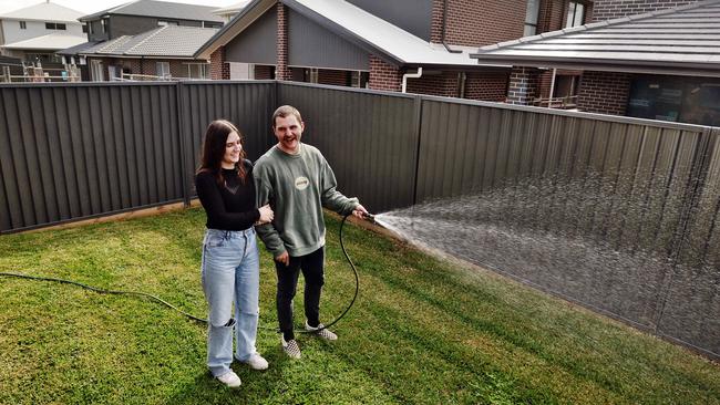 Tristan Tipler and his partner Stevie-Lyn Ritchie pictured watering the grass in their small backyard at Marsden Park. Picture: Sam Ruttyn