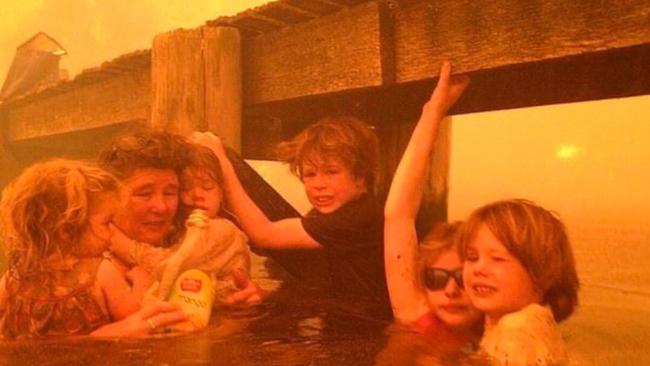 A family clinging to a jetty to escape fires. Picture: Tim Holmes