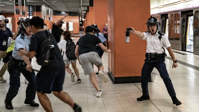 A police officer holds up pepper spray as he attempts to disperses protesters out of the platform at Po Lam Station in Hong Kong. Picture: Getty Images