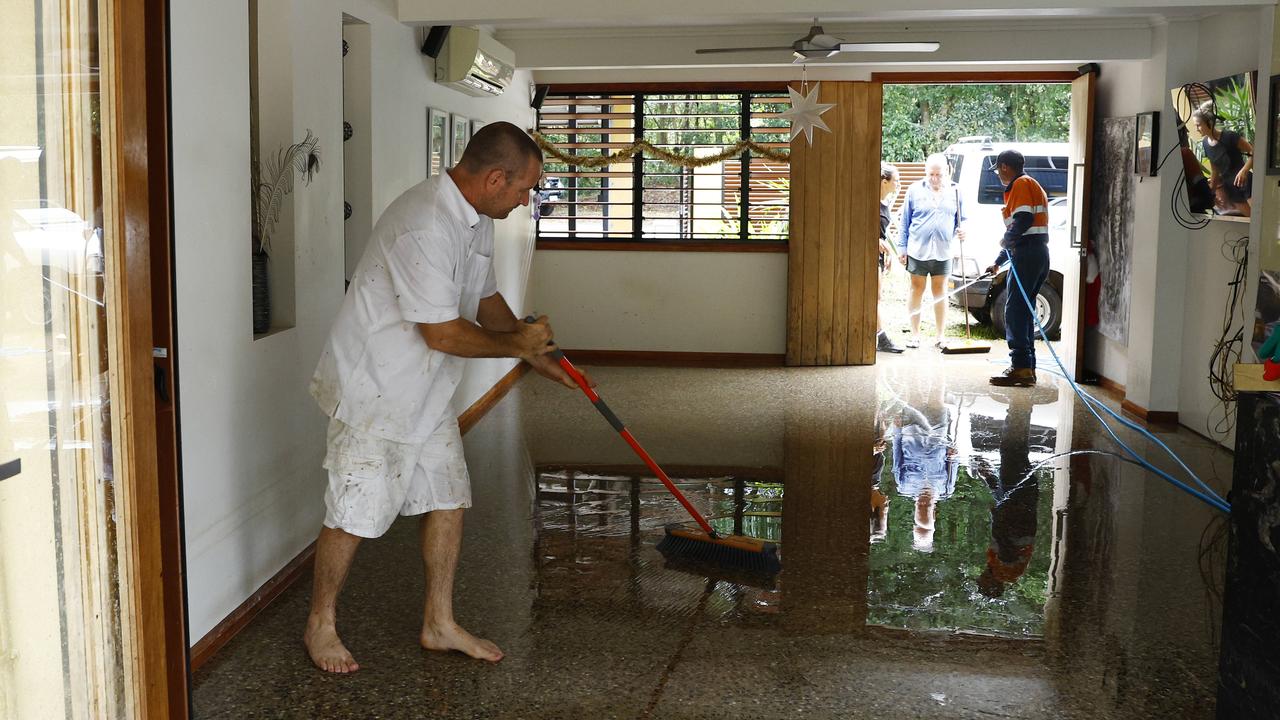 Garry Henry sweeps flood water out from a house at Caravonica, Cairns. Picture: Brendan Radk