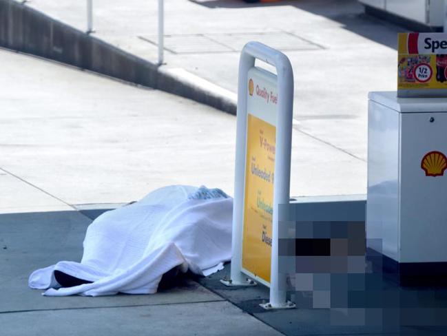 The body of a Darren Wallace at the Coles Express Shell service station in Picton is covered in a sheet on the forecourt.