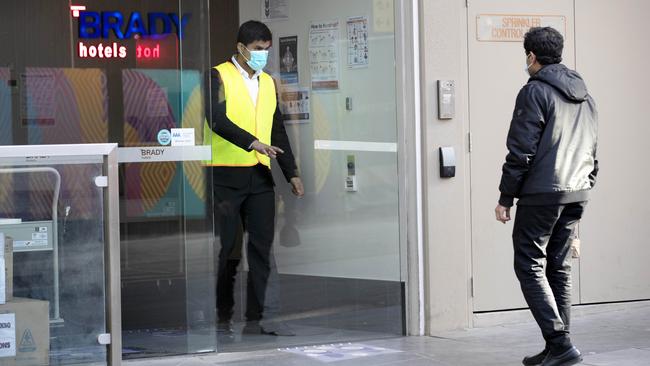 A staff member lets a man in the front door of the Brady Hotel, which has been given the contract to act as the state’s quarantine hub. Picture: David Geraghty