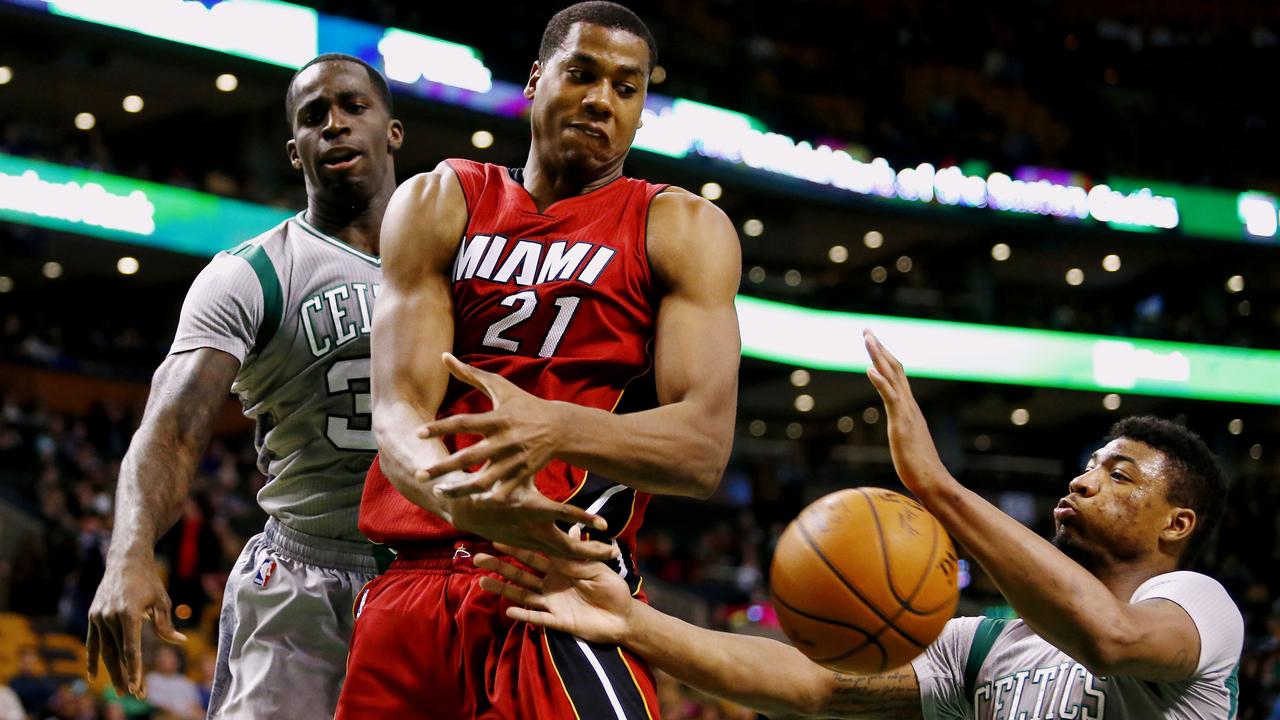 Miami Heat center Hassan Whiteside (21) makes a pass between Boston Celtics' Brandon Bass and Marcus Smart (36) during the second half of an NBA basketball game in Boston, Sunday, Feb. 1, 2015. Miami defeated Boston 83-75. (AP Photo/Winslow Townson)