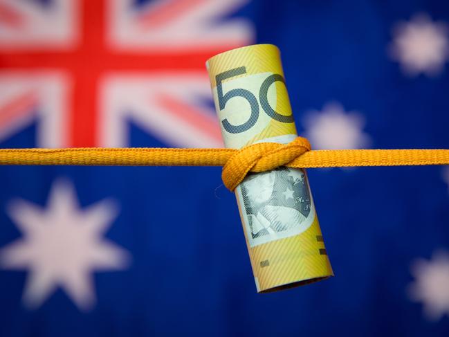 Studio shot close up of an Australian dollar note tied in a knot with the Australian flag as a background. Mortgage home loan money stress generic