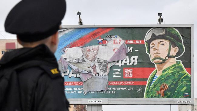 A military cadet stands in front of a billboard promoting contract army service in Saint Petersburg on October 5, 2022.