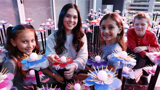 Gemma Ferguson, 22, is one of the youngest light artists involved in Vivid Sydney 2022 and worked with hundreds of Sydney primary school students to create a mass installation of light flower. She is pictured here with (from left) seven-year-old Avalon Elsley, seven-year-old Ava Corcoran and eight-year-old Lachlan Oliver 8. Picture: Tim Hunter.