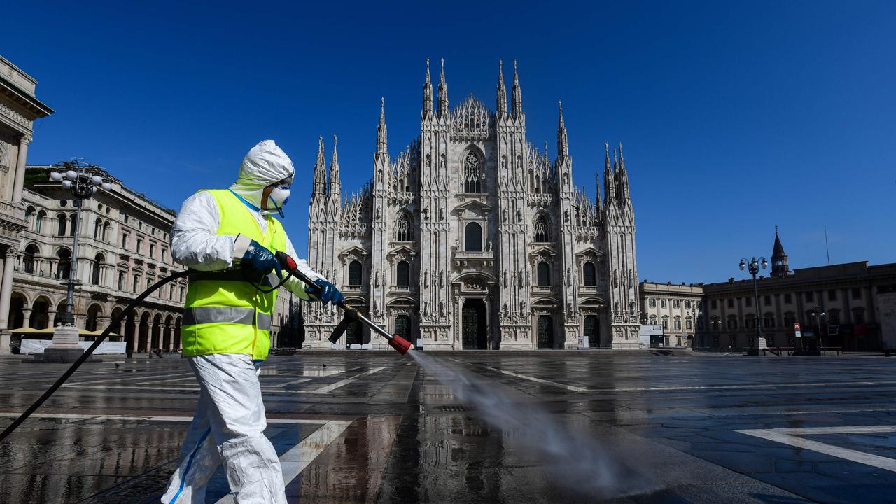 An employee wearing protective gear sprays disinfectant on Piazza Duomo in Milan, which is otherwise completely deserted. (Photo by Piero Cruciatti / AFP)