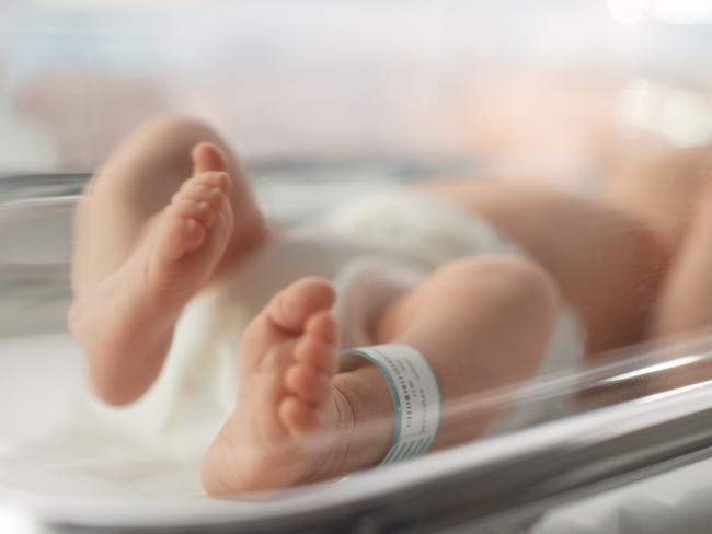 Cute Little Caucasian Newborn Baby Lying in Bassinet in a Maternity Hospital. Portrait of a Tiny Playful and Energetic Child with a Name ID Tag on the Leg. Healthcare, Pregnancy and Motherhood Concept