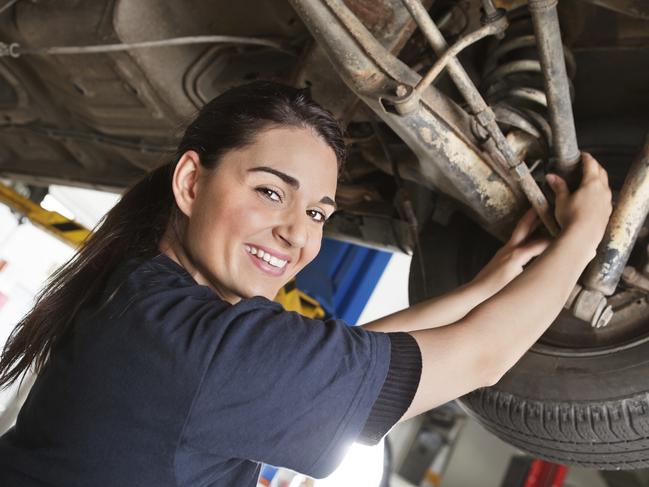 Portrait of smiling young female mechanic inspecting a CV joing on a car in auto repair shop. Free to use from iStock