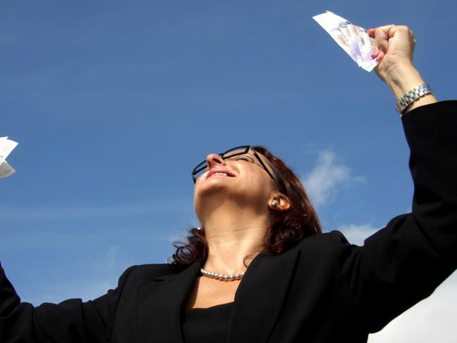 Feeling of success. Generic image of a happy woman looking up at blue sky, holding lottery tickets and smiling.